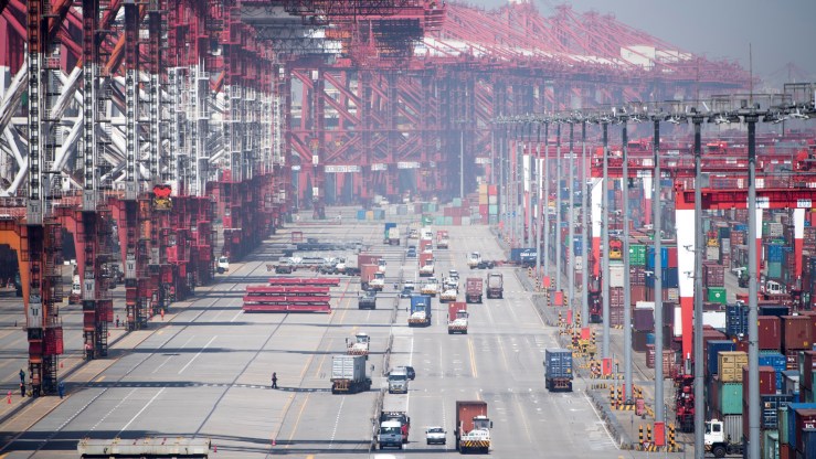 Trucks move under cranes and past shipping containers in Shanghai's Yangshan Port.