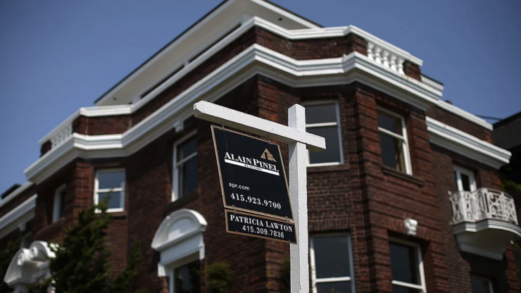 A for sale sign is seen in front of a brick home in San Francisco.