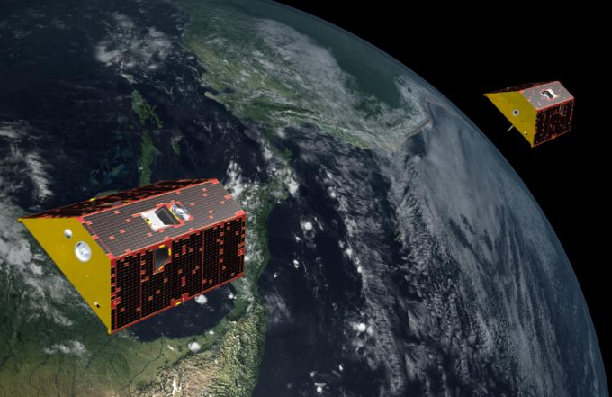 Two illustrated yellow, red and black trapezoid-satellites orbit the Earth.