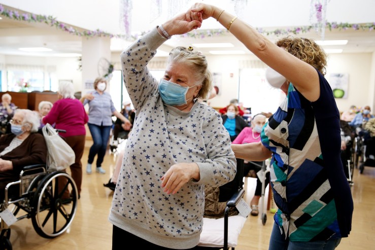 Two ladies dance together during a party at an assisted living facility.