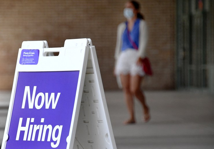Pedestrians walk by a "Now Hiring" sign outside a store on August 16, 2021 in Arlington, Virginia.
