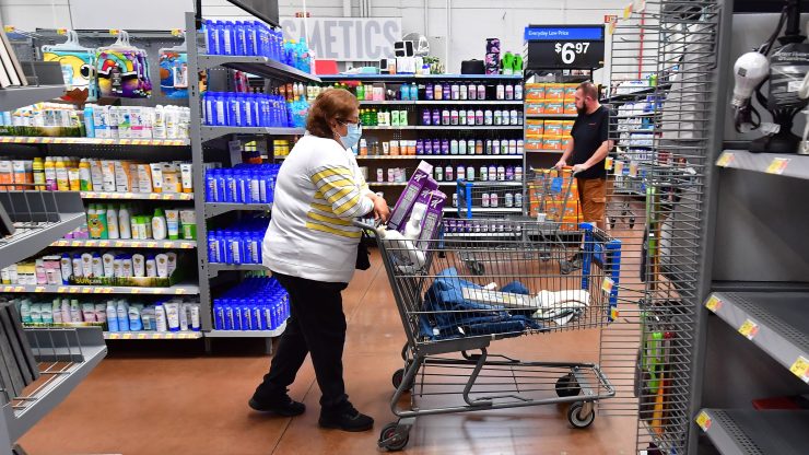 Woman pushing a shopping cart walks through the toiletries aisle at a supermarket.