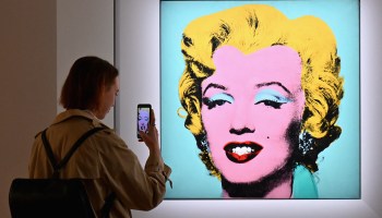 A woman takes a photo of Andy Warhol's 'Shot Sage Blue Marilyn' at Christie's in New York City.