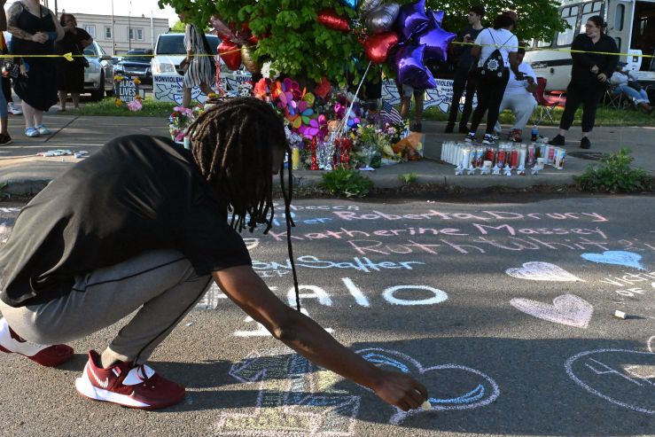 A Black man draws a heart in chalk on the ground at the vigil for shooting victims in Buffalo, New York.