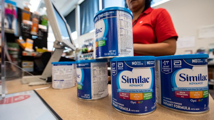 Cans of formula are stacked on top of one another on a pantry counter.