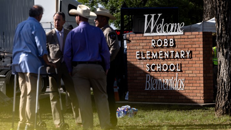 Law enforcement and yellow tape is seen in front of the Welcome sign for Robb Elementary School, where 19 children and two adults were killed in a mass shooting.
