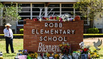 The Robb Elementary School sign is lined with flowers left by mourners.