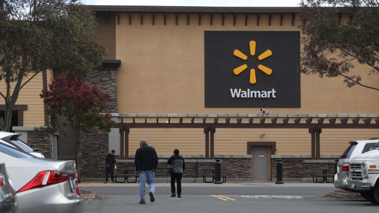 Customers walk outside a Walmart store with the company's logo prominently displayed.
