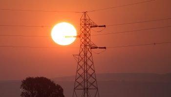 Electrical tower in front of a setting sun.