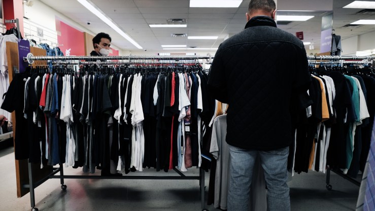 Two men shop among shirt racks.