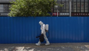 Health care worker clad in a hazmat suit walks along a street in Beijing.
