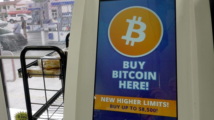 A bitcoin ATM at a store, with the phrase "BUY BITCOIN HERE!" on the screen.