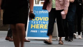 People walk past a COVID testing site.