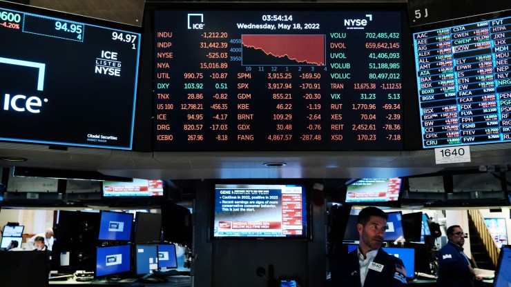 Traders work on the floor of the New York Stock Exchange. Stock market numbers are shown, mostly in the red.
