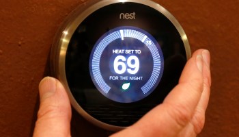 A Nest thermostat being adjusted. It reads, "Heat set to 69 degrees for the night."