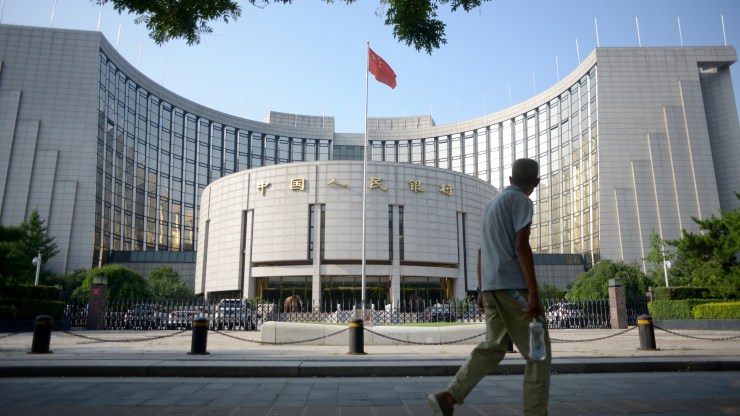An elderly man walks past the exterior of the People's Bank of China in Beijing.
