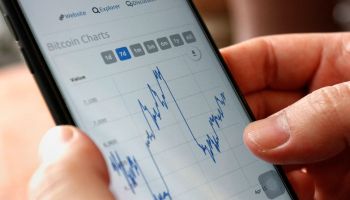 A cryptocurrency investor looks at Bitcoin charts on a smartphone.