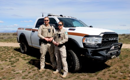 Idaho State Chief Ranger for the BLM Becky Andres and BLM Officer Bryan Adams stand in front of a BLM truck on public lands outside Boise, Idaho.
