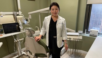 Dr. Mina Kim poses in front of a dentist's chair at her Manhattan office.