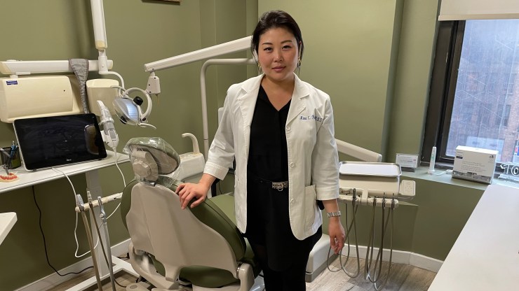 Dr. Mina Kim poses in front of a dentist's chair at her Manhattan office.