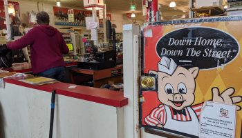 A checkout employee works at a Piggly Wiggly on its last day.