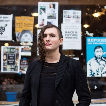 A photo of Evan Greer, director at the digital rights advocacy group Fight for the Future, in front of a window with posters.