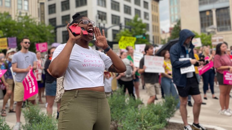 Tia Freeman is seen shouting at a protest, with other protesters behind her.