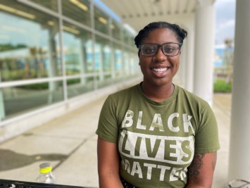 Tia Freeman smiles for a portrait, wearing glasses and a Black Lives Matter t-shirt.