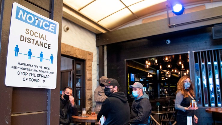 A notice inviting patrons to social distance is seen in the outdoor seating area of The Abbey Food & Bar.