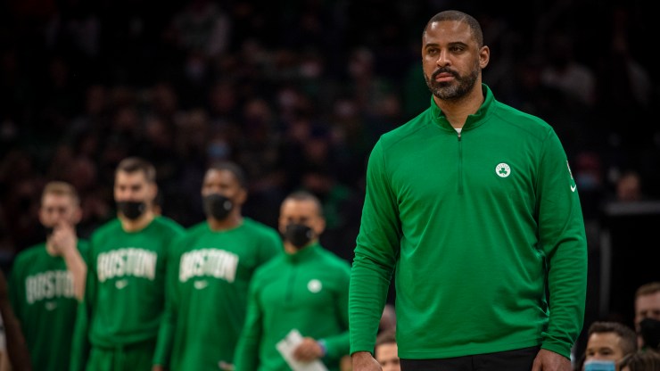Head Coach Ime Udoka of the Boston Celtics looks on from the sidelines during the first half of a game against the Phoenix Suns at TD Garden on December 31, 2021 in Boston, Massachusetts. Some Boston Celtics players and coaches stand in the background watching the game, too.