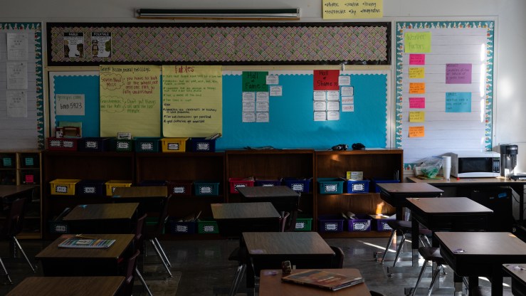 A classroom sits empty and dark. Unused desks and cubbies are visible.