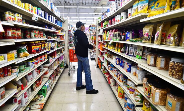 A man stands in the middle of a grocery store aisle.