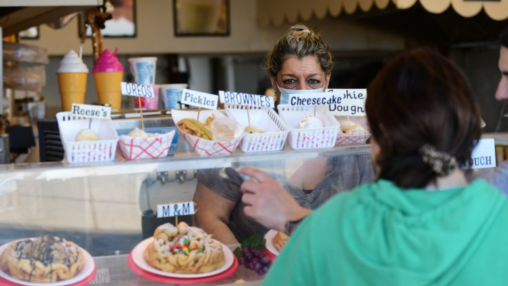 A woman wears a mask while serving boardwalk patrons funnel cakes Pon May 30, 2022 in Wildwood, New Jersey.