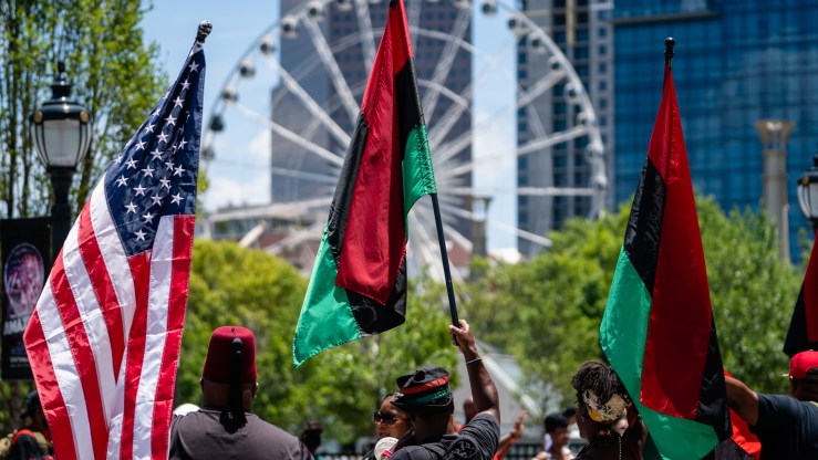 People raise American and Pan-African flags while marching in the Juneteenth Atlanta Black History parade.