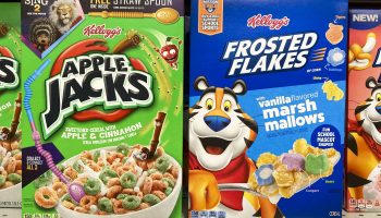 A closeup of Apple Jacks and Frosted Flakes cereals on a grocery store shelf.