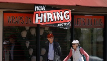Pedestrians walk by a "Now Hiring" sign in front of a boxing gym in San Rafael, California.