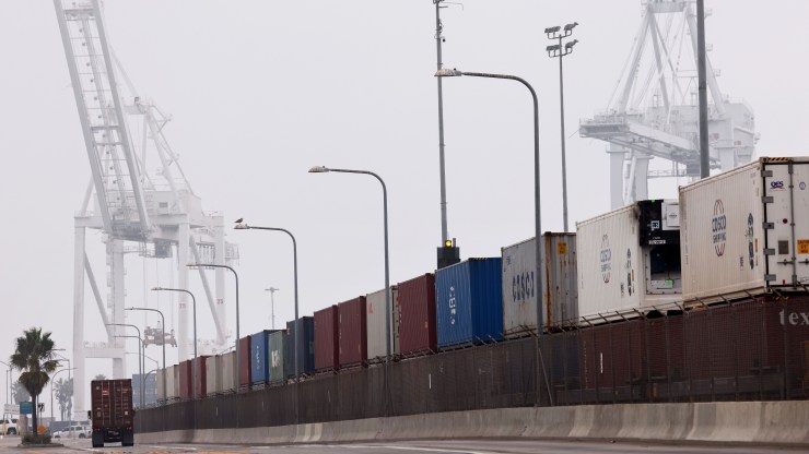 An 18-wheeler drives past stacks of shipping containers at the Port of Long Beach.