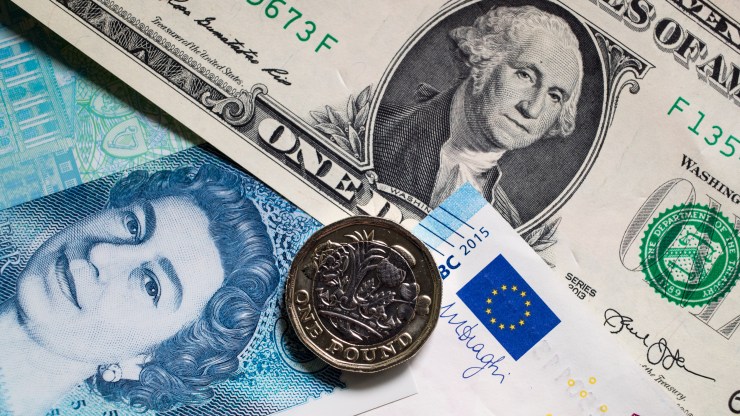 A U.S. dollar bill is seen amid euro notes and a £1 pound coin.