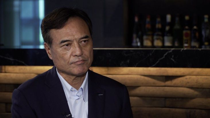 CEO Takeshi Niinami is seen in front of a dimly lit bar.
