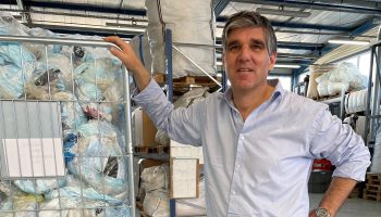 Plaxtil co-founder Jean-Marc Neveu stands and grabs a large bin of face masks soon to be recycled into plastic objects.