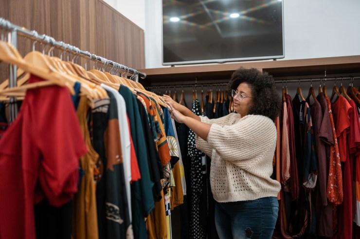 A woman browses through a rack of clothing.