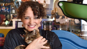 Angeli Rodriguez holds a cat, Biscuit. A coffee shop is behind them.