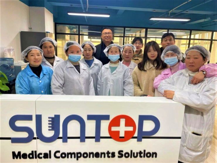 Colin Zhao and his staff stand behind a sign reading "Suntop Medical Components Solution."