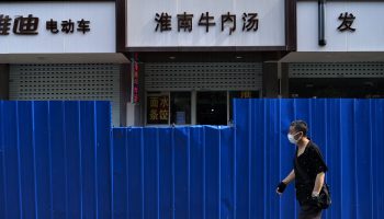 A masked person walks past a boarded-up street in Shanghai.