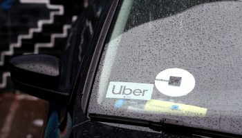 A car's windshield includes a small rectangular sign that says, "Uber."