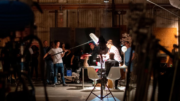 Actors and crew work on an indoor scene.