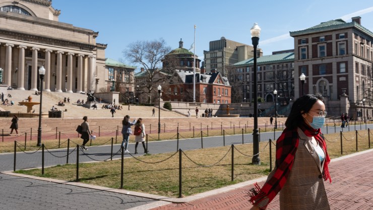 A woman wearing a face mask walks on the Columbia University campus.