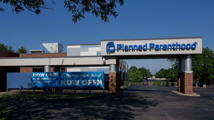 The exterior of a Planned Parenthood office, with blue sign that reads "Now Open"