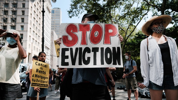 An activist holds a "Stop Eviction" sign at a rally.