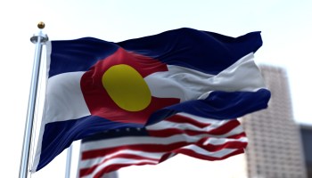The Colorado state flag flies alongside the American flag.